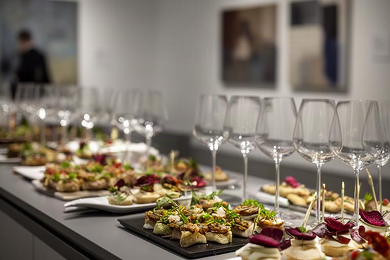 Buffet con finger food e calici allestito in un museo durante un vernissage